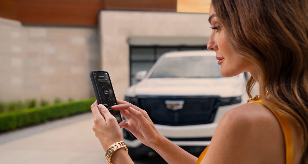 lady checking her mobile with a Cadillac vehicle background | Alfred Matthews Cadillac in Modesto CA